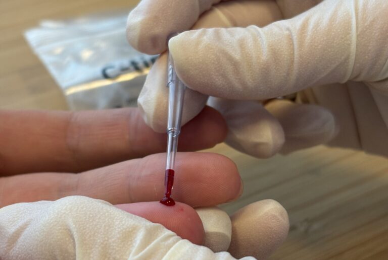Bild einer Testung mit Blutabnahme an einem Finger
